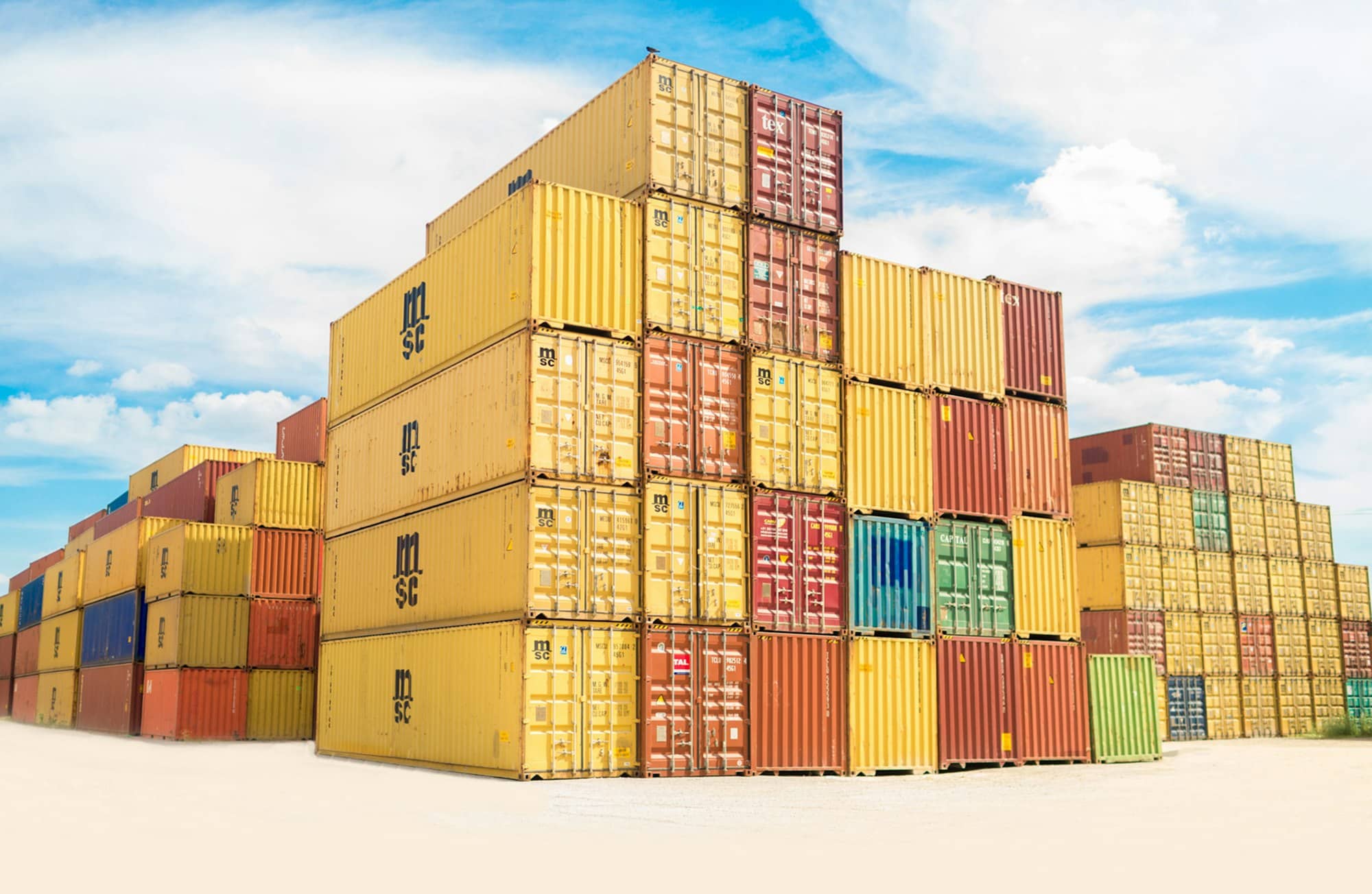 Stacks of colourful shipping containers under a blue sky