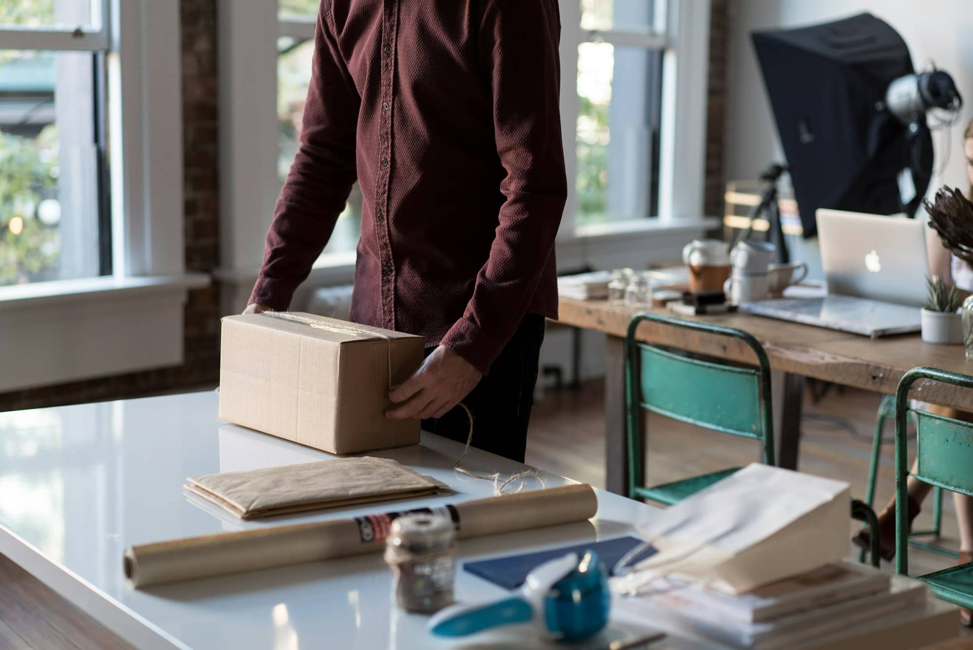 A person sealing a cardboard parcel on a desk