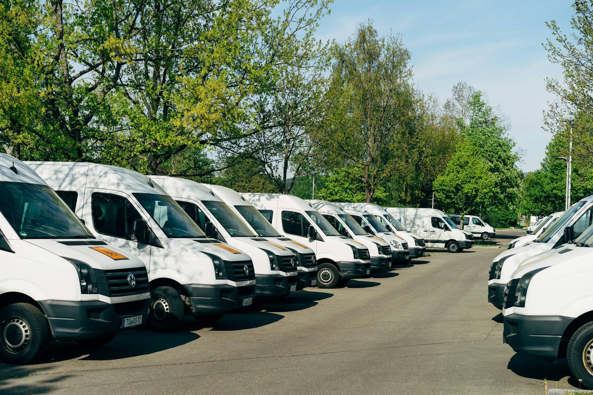 A row of white delivery vans parked in a lot